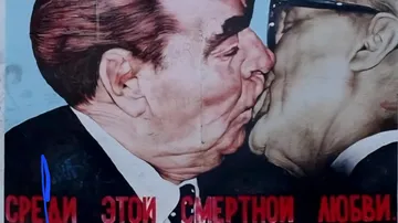 Two men kissing passionately with blue background.