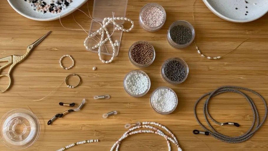 Beading supplies arranged on a wooden table.