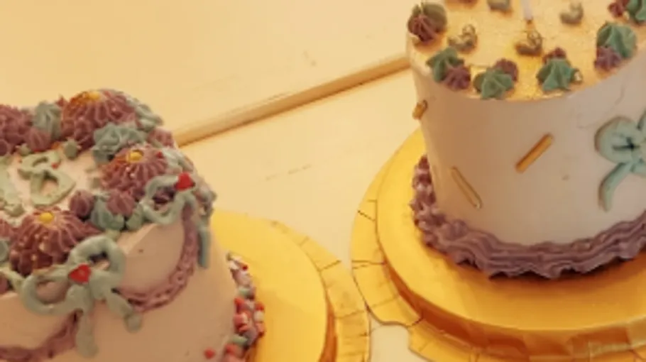 Two decorated cakes on gold trays.
