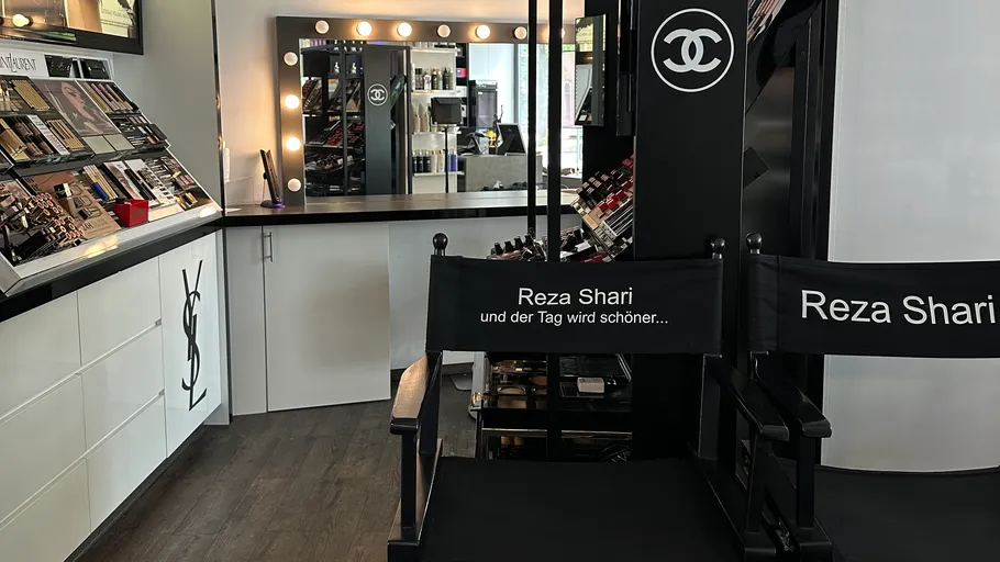 Make-up-Studio mit Stühlen und Produkten dargestellt.
