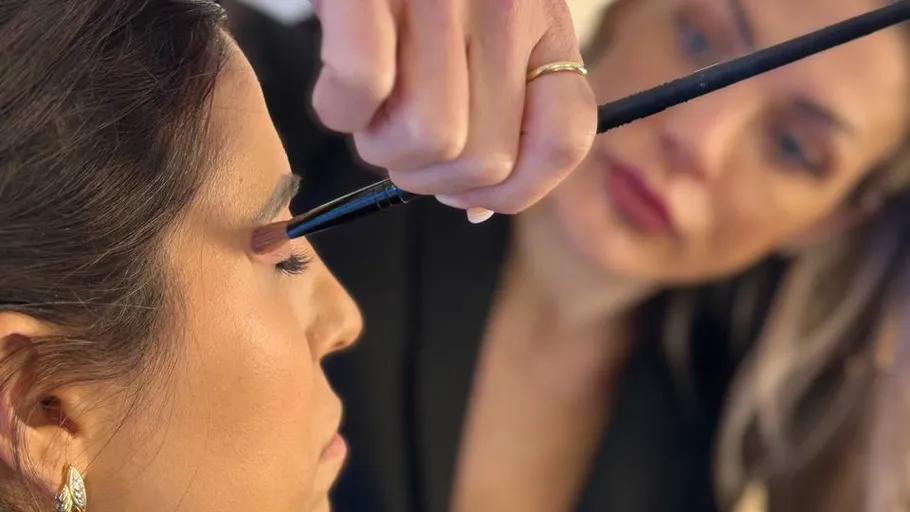 Makeup artist applying eyeshadow on woman.
