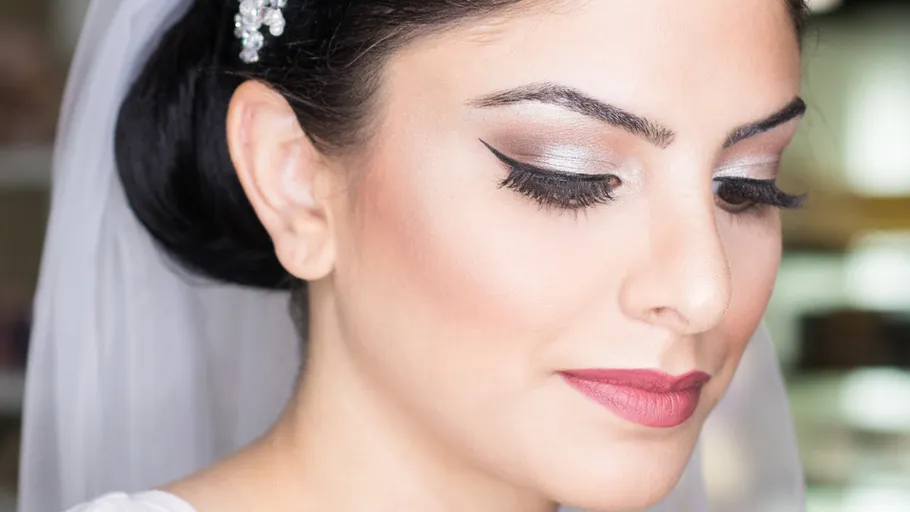 Braut mit elegantem Make-up und Schleier drinnen.