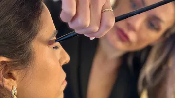 Woman applying eyeshadow to another woman.