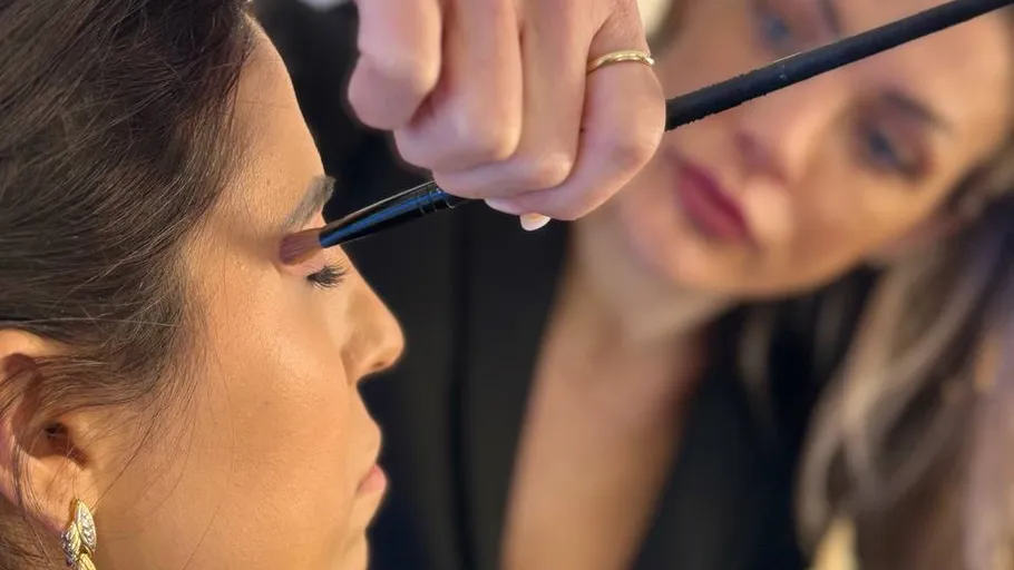 Woman applying eyeshadow to another woman.