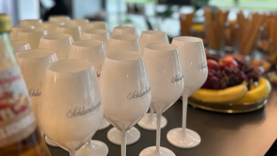 Weiße Gläser mit Logo auf einem Tisch.