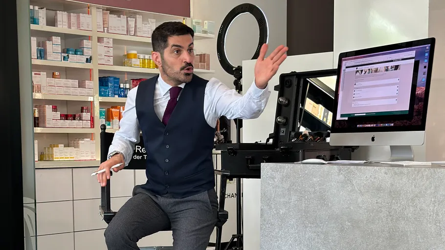 Man gesturing while seated near computer.