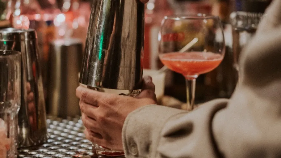 Barkeeper schüttelt Cocktailshaker hinter Bar.