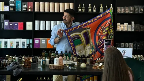 Man shows colorful scarf in perfume shop.