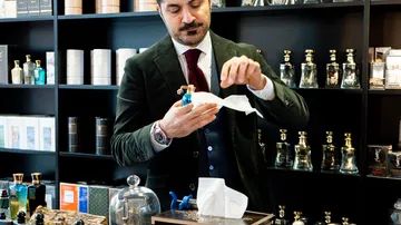 Man cleaning a perfume bottle in a shop.