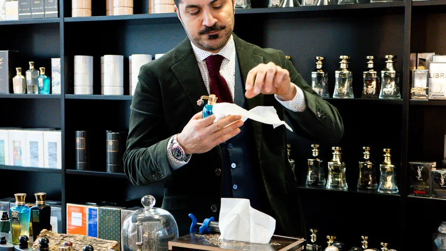 Man cleaning a perfume bottle in a shop.