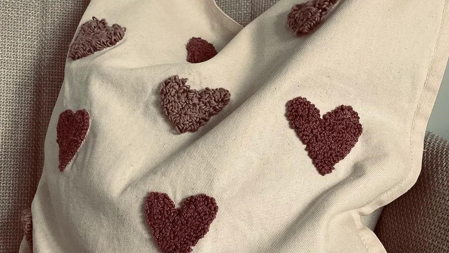 Beiges Kissen mit strukturierten Herzmustern.