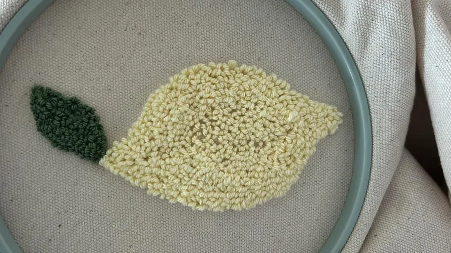 Lemon punch needle embroidery with green leaf.