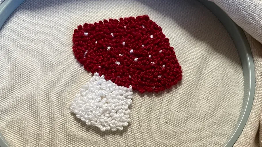 Embroidery of red mushroom on fabric.