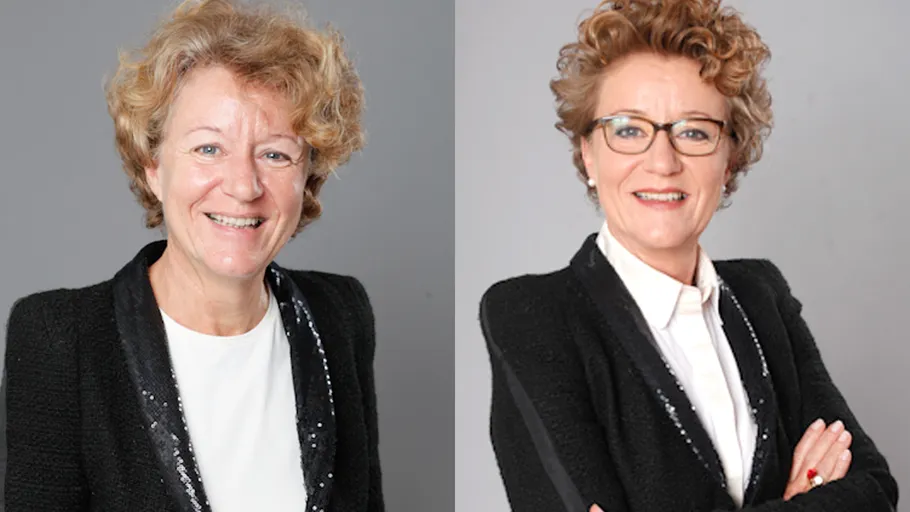 Two women smiling, wearing black jackets.