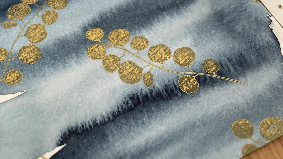 Goldene Blätter auf blauem Aquarellhintergrund.