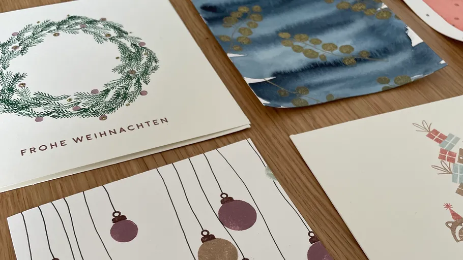 Weihnachtskarten mit festlichen Designs auf Tisch.
