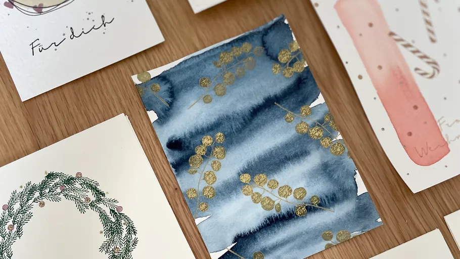 Künstlerische Karten mit Aquarellmustern auf Tisch.