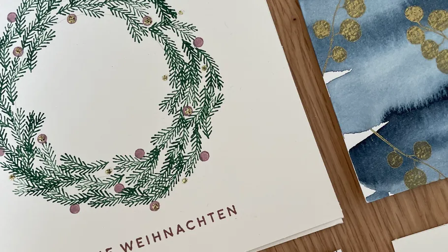 Weihnachtskarte mit Kranz auf Tisch.