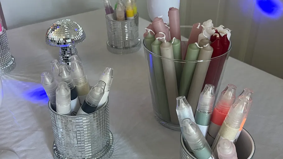 Assorted pens and candles on a white table.