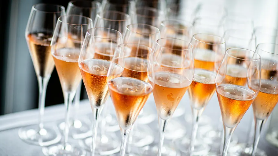 Glasses filled with rosé champagne on table.