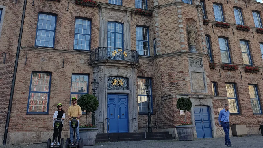 Zwei Personen auf Segways vor Ziegelgebäude.