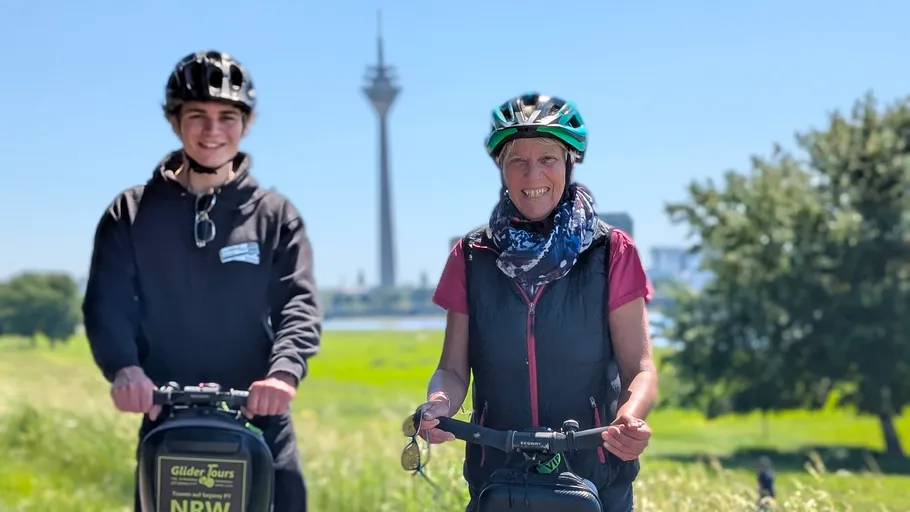Two people riding segways near a tower.