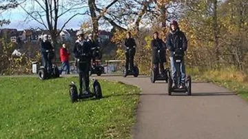 Menschen fahren Segways auf einem Parkweg.