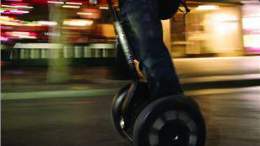 Person fährt Segway auf Stadtstraße.