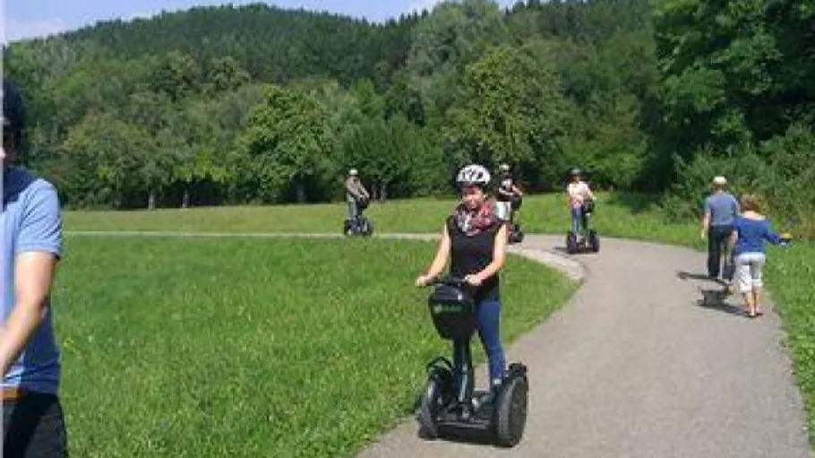 People riding Segways on a path with trees.