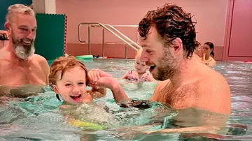Adults and children swimming in indoor pool.