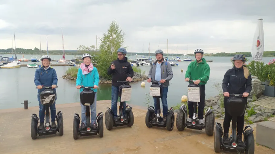 Sechs Personen auf Segways an einem Yachthafen.