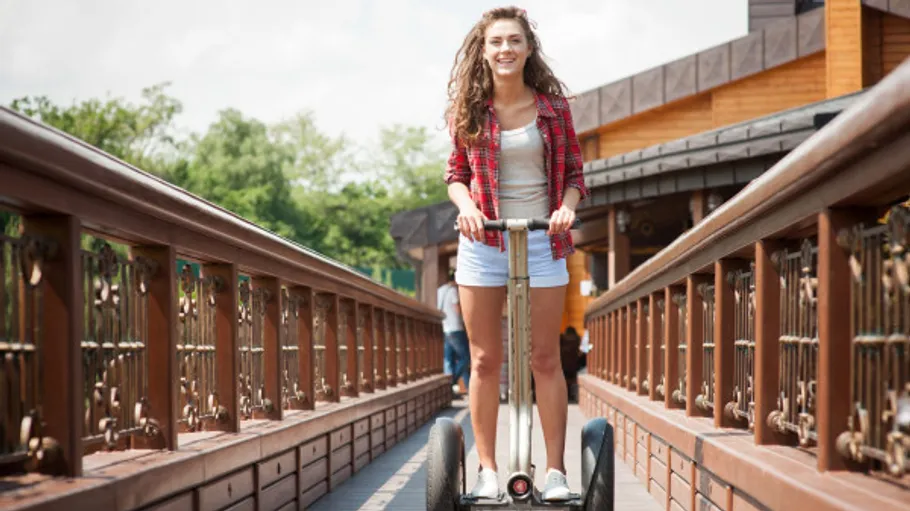 Frau fährt Segway auf einer Holzbrücke.