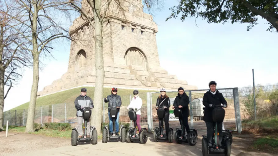 Gruppe fährt Segways nahe einem Denkmal.