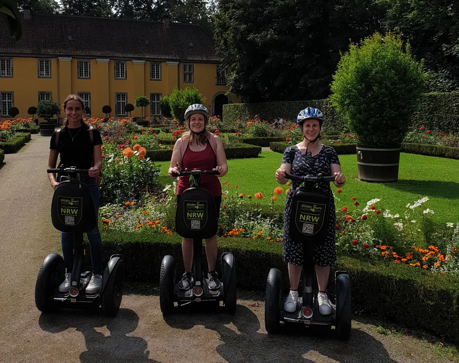 Three people on Segways in a garden.