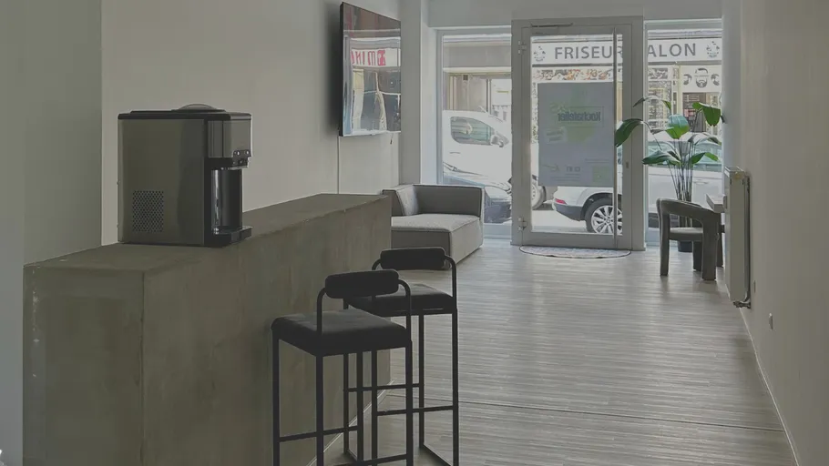 Modern kitchen area with seating and coffee machine.