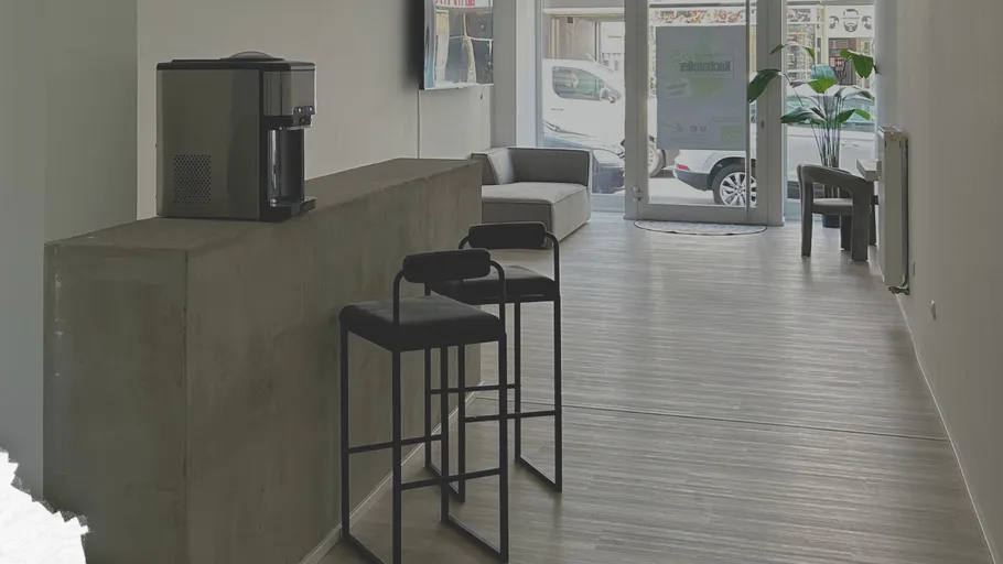 Modernes Büro mit hohen Barhockern und Kaffeemaschine.