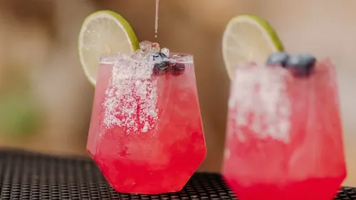 Pink cocktails with lime and blueberries outdoors.