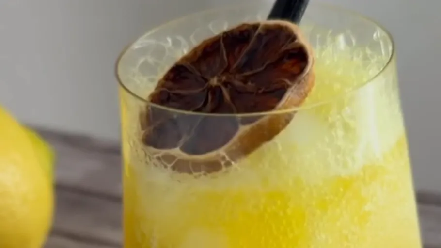 Yellow drink with dried lemon slice garnish.