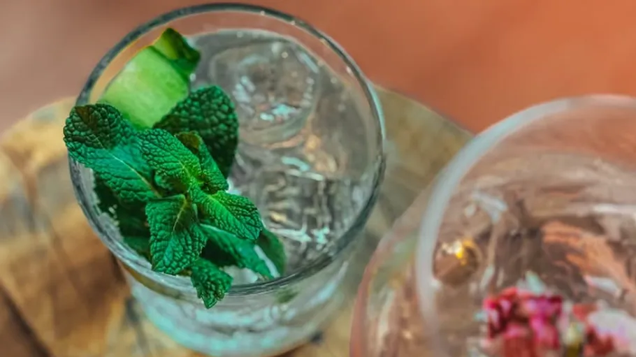 Glass with mint and cucumber on table.