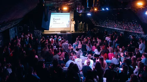 Person speaking on stage to seated audience.