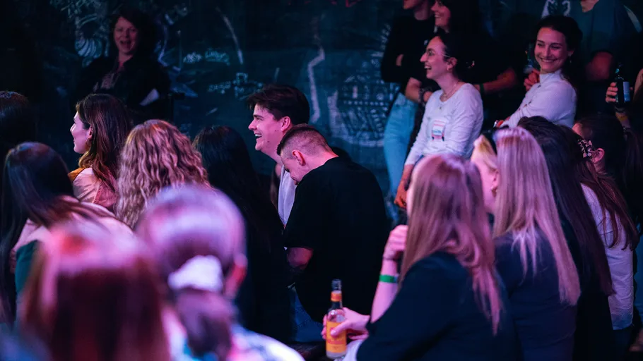 Publikum lacht bei Comedy-Show in dämmerigem Licht.
