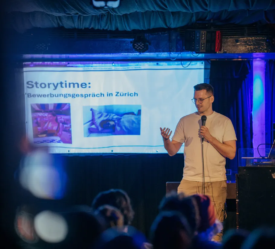 Man presenting on stage with projected slide.