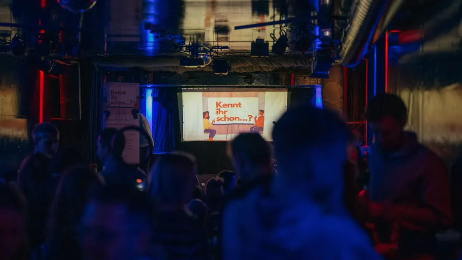 Menschen in einem dunklen Club mit Leinwand.