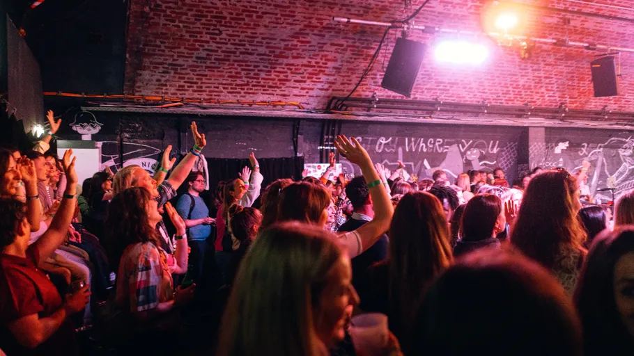 Crowd of people, hands raised, inside a venue.