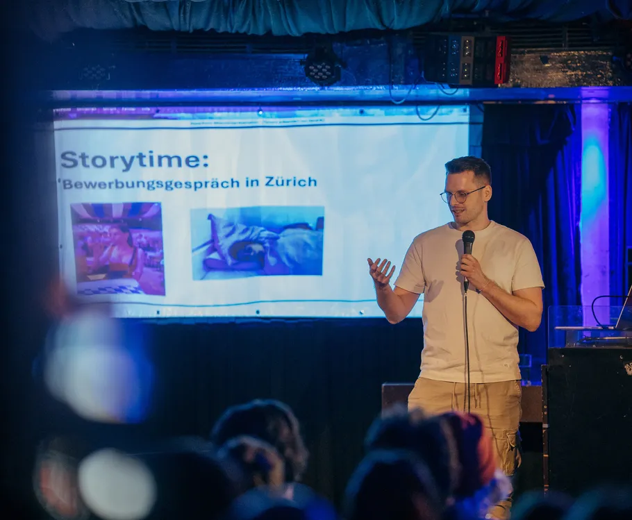 Man giving presentation on stage with slideshow.