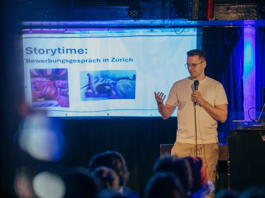 Person presenting on stage with projected slide.