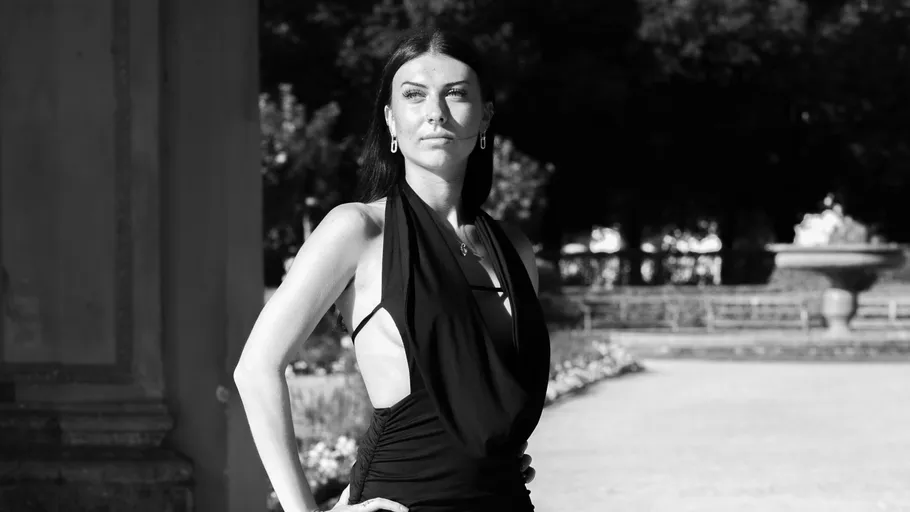 Frau posiert selbstbewusst im eleganten Kleid draußen.