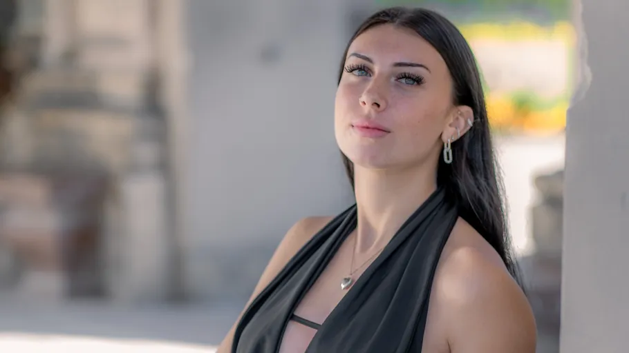 Frau im schwarzen Kleid steht draußen.