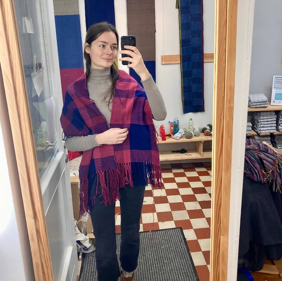 Frau trägt Schal, macht Spiegel-Selfie drinnen.