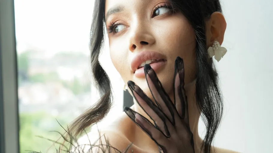 Woman with black gloves looking out window.